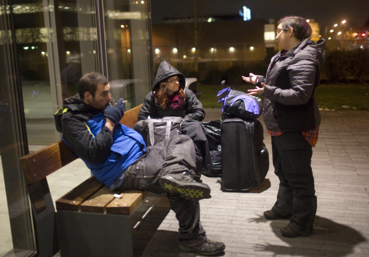 Housing case manager, Jamie Spinelli, right, asks Anthony Bordelon and Mandy Seitz what items they need to keep warm Dec. 17 outside the Vancouver Community Library. Volunteers with the nonprofit organization Food with Friends hand out food and other items to the homeless Saturday nights in downtown Vancouver.