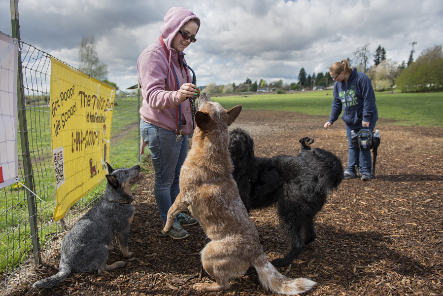 Jordan Richards of Camas, in pink sweatshirt, shares treats at Stevenson Off Leash Dog Park in April. The Washougal park closed in November but will reopen temporarily in January and remain open through April 28.