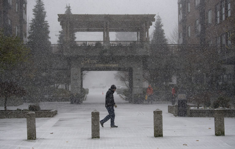 A pedestrian walks through a snow shower in downtown Vancouver on Thursday afternoon, Dec. 8, 2016.