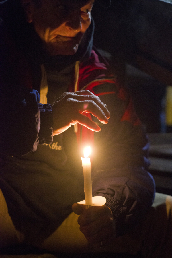 Robert Langford warms his hand with a candle during a homeless memorial service Wednesday night at St. Paul Lutheran Church in Vancouver.