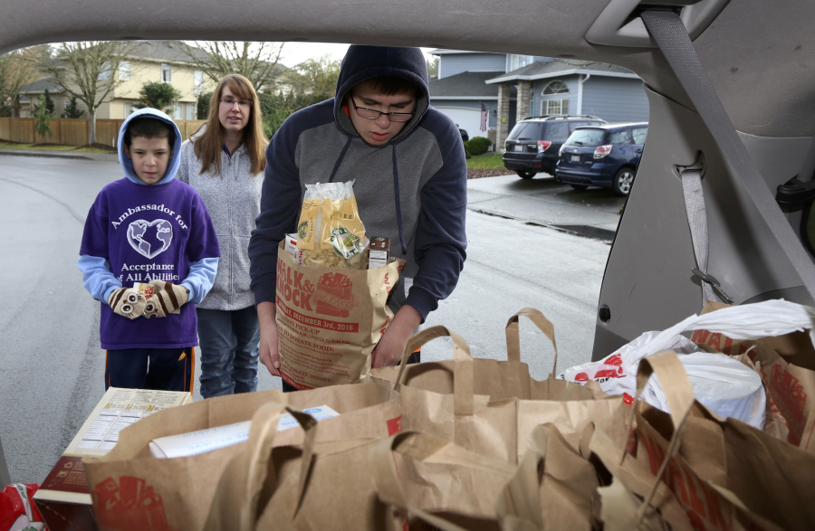 Thirteen-year-old Zachary Borghello, from left, Kim Prather and Josh Prather, 14, load donated food into the Autism Serves Kids Care Club&#039;s minivan in Saturday&#039;s Walk &amp; Knock.