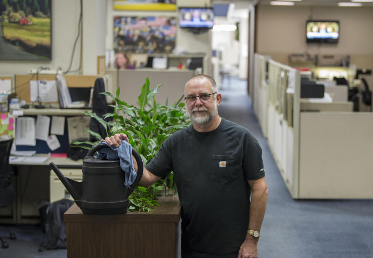 Todd Marquiss is pictured with plants he helps care for in the newsroom at The Columbian.