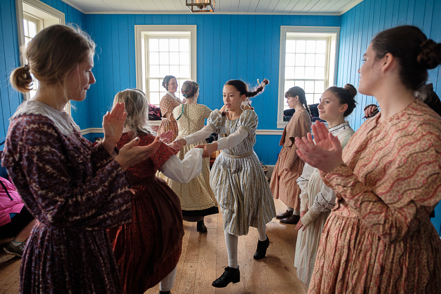 Volunteers in 1840s costume perform a line dance at Christmas at Fort Vancouver on Saturday.