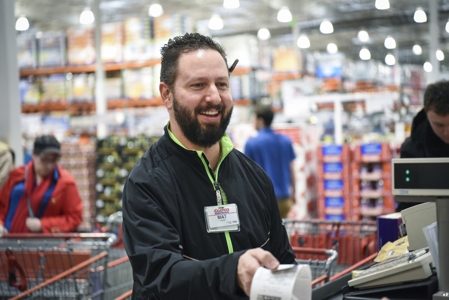 Costco employee Mathew Rios hands a receipt to a customer at checkout Tuesday in Vancouver. Rios, who has been a Costco employee for 22 years, helped save the life of an elderly woman Friday, after she collapsed in the checkout line at the store. He administered CPR for more than five minutes.