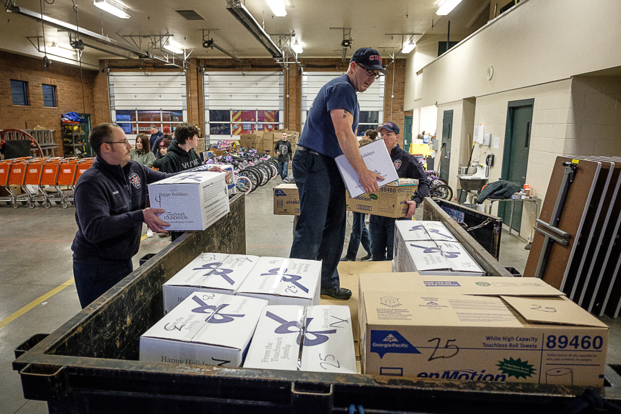 Camas-Washougal firefighter Jeff Martizia, center, loads packages of toys and food Wednesday at Station 42. They will be distributed to families in need around Camas and Washougal.