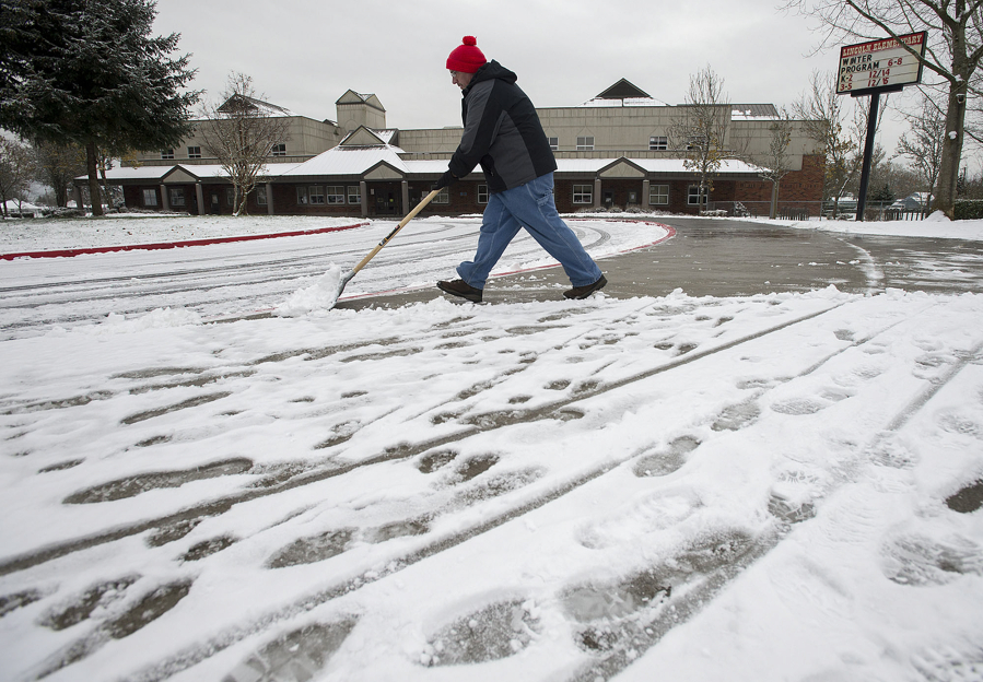 Lincoln Elementary School building operator Gene Boyer clears the sidewalk outside the school on Dec. 15, one of four snow days already this school year.