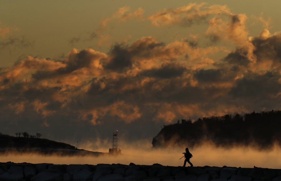Darryl Hendricks moves into position on a breakwater to photograph sea smoke rising off the waters of Casco Bay Friday in South Portland, Maine. Hendricks risked both frost bite and being late for work in pursuit of what he called &quot;the one shot I really wanted.&quot; The temperature dropped to minus-2 degrees Fahrenheit with a wind chill of minus-25. (AP Photo/Robert F.