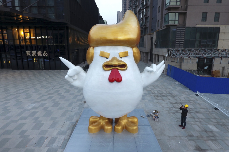 A worker takes a picture of a giant rooster sculpture resembling U.S. President-elect Donald Trump on display outside a shopping mall to celebrate the upcoming Chinese Year of the Rooster in Taiyuan in north China&#039;s Shanxi province Thursday. Trump has vowed to label China a currency manipulator on his first day in the White House. He says Beijing keeps its currency low to unfairly benefit its exporters. But he&#039;ll struggle to prove the case if it goes before the World Trade Organization: Economists say China isn&#039;t meddling in markets to push the yuan lower; it&#039;s doing the opposite, trying instead to keep it from falling faster.