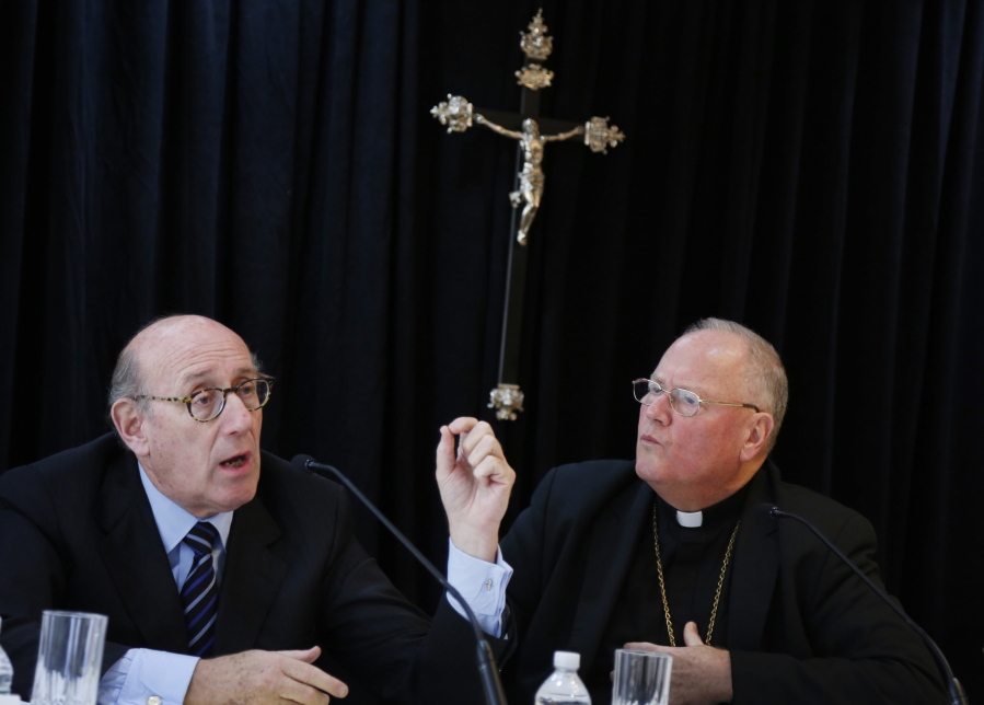 FILE - In this Oct. 6, 2016 file photo, Cardinal Timothy Dolan, Archbishop of New York, right, listens as Kenneth Feinberg speaks to reporters during a news conference in New York announcing a new program intended to provide reconciliation and compensation for victims of sexual abuse by clergy. The new compensation process set up by the Archdiocese of New York itself, potentially the most extensive effort of its kind to date, lets people take claims, often too old for court, to a noted outside mediator while keeping painful details private.