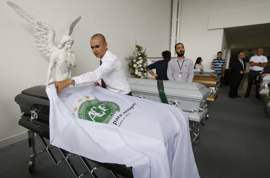 A funeral home employee places a sheet with a Chapecoense soccer team logo over the casket of a team member Thursday in Medellin, Colombia.