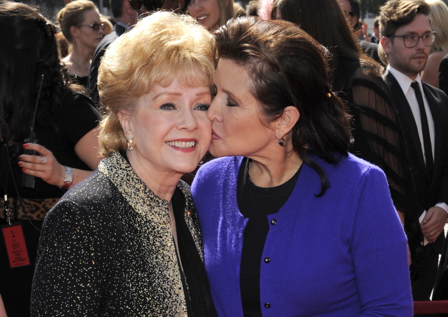 Carrie Fisher kisses her mother, Debbie Reynolds, on Sept. 10, 2011, as they arrive at the Primetime Creative Arts Emmy Awards in Los Angeles. Reynolds, 84, died Dec. 28, one day after Fisher, 60, died.