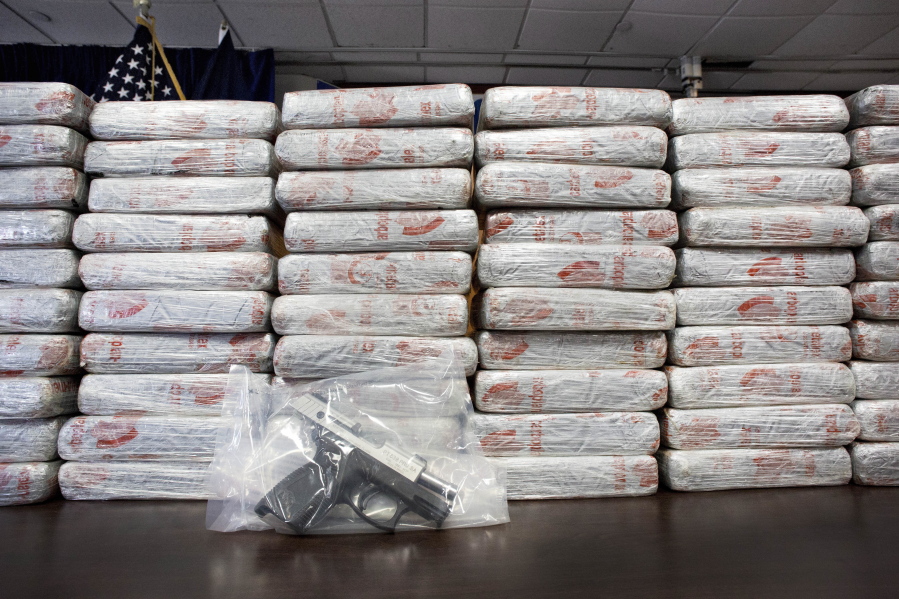 A firearm is seen amid a backdrop of 154 pounds of heroin worth at least $50 million displayed during a Drug Enforcement Administration news conference in May 2015 in New York. According to government data released Thursday, drug overdose deaths in the U.S. surpassed 50,000 in 2015, the highest mark in at least 15 years.
