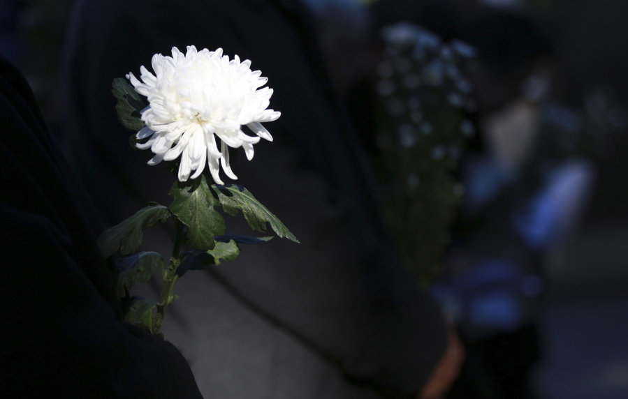 A group of Japanese hold white chrysanthemum flower at the cemetery alter to pray for soul of the war dead at a national cemetery for unnamed soldiers of World War II in Tokyo Wednesday. Dozens of Japanese gathered Wednesday afternoon to demand Japanese leader Shinzo Abe also pay a visit to the sites across Asia that came under attack by Japan during times of war,  following Abe&#039;s historical visit to Pearl Harbor on Dec. 27 in Hawaii, U.S.