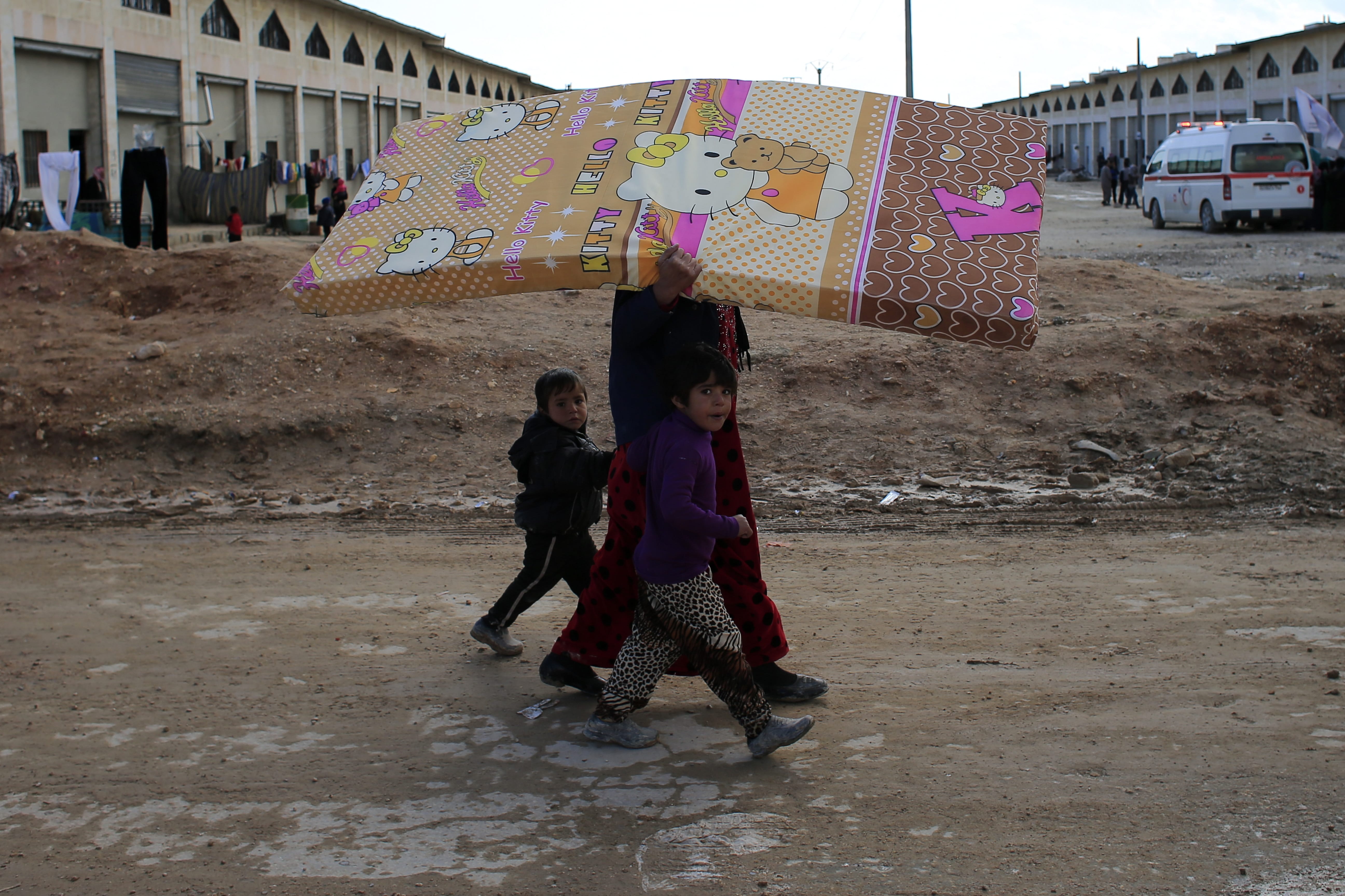 A Syrian woman displaced with her family from eastern Aleppo walks with her children as she carries a mattress in the village of Jibreen south of Aleppo, Syria, Saturday, Dec. 3, 2016. Aid agencies say that more than 30,000 people have fled rebel-held eastern neighborhoods of Aleppo that have been under tight siege since July.