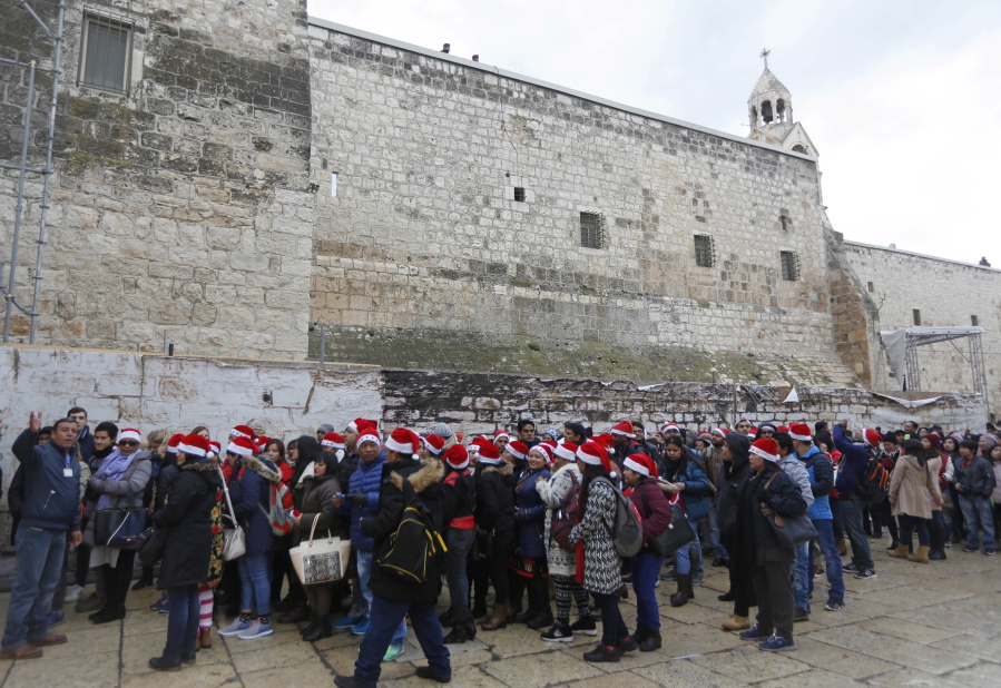 Christian pilgrims wearing red Santa hats wait in line to enter the Church of the Nativity, built atop the site where Christians believe Jesus Christ was born, on Christmas Eve, Dec. 24, in the West Bank City of Bethlehem.