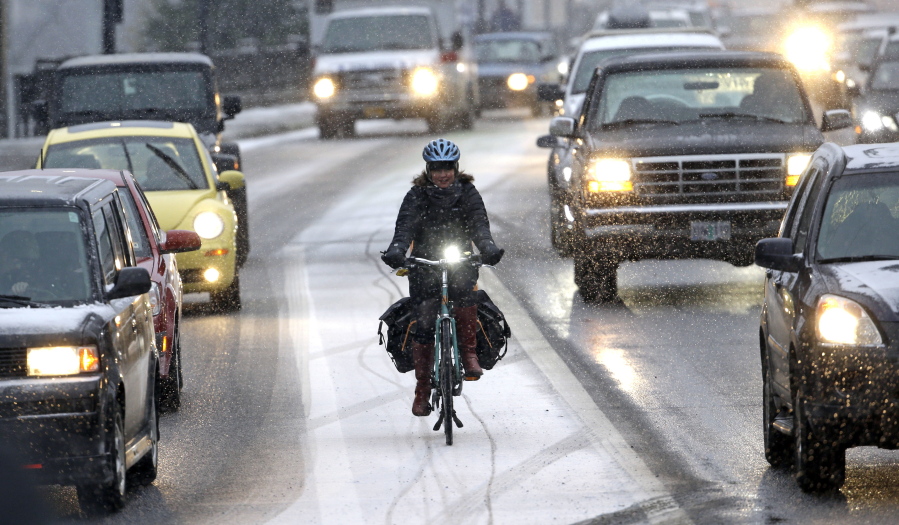 A bicyclist is surrounded by heavy traffic as a snow storm forces commuters to leave the city early and jam roads and freeways in Portland, Ore., on Wednesday.