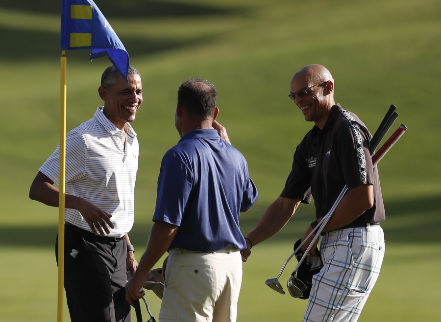President Barack Obama, left, smiles after putting on the 18th green on Dec. 21 at Kapolei Golf Club in Kapolei, Hawaii. Golfing with the president are Bobby Titcomb, center, and Darrell Harrington.
