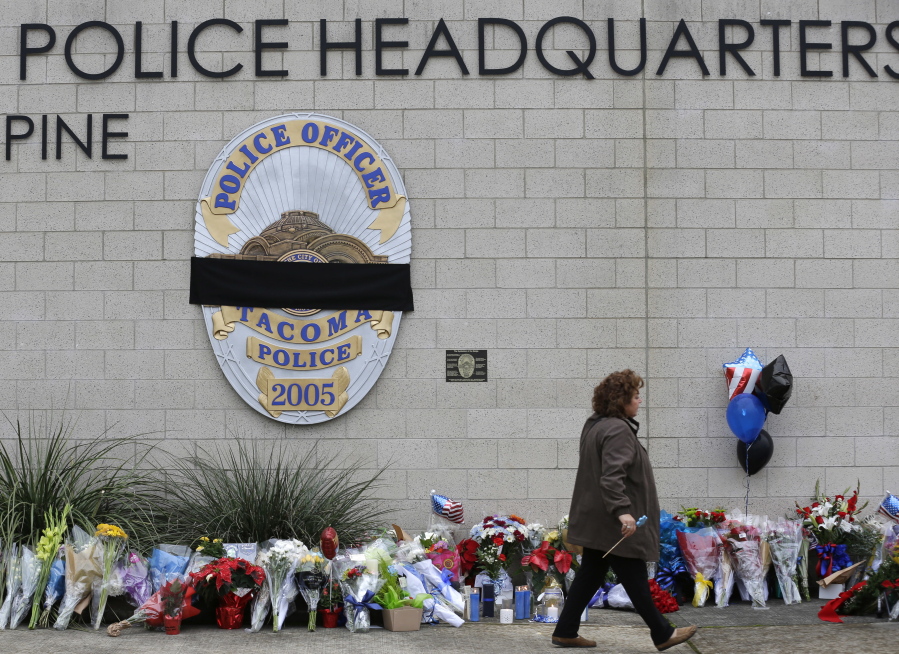 A visitor walks past the growing memorial at Tacoma Police Headquarters on Thursday in memory of Tacoma Police Officer Reginald &quot;Jake&quot; Gutierrez. Gutierrez was shot while responding to a domestic violence call Wednesday and died later in the day at a hospital. (AP Photo/Ted S.