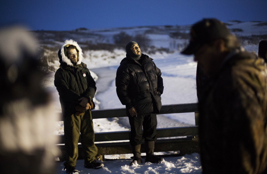 Canadian combat veteran James Pitawanakwat, right, a member of the Anishinaabe Native American tribe, sings a traditional song during a protest across from police protecting the Dakota Access oil pipeline site in Cannon Ball, N.D., Thursday, Dec. 1, 2016. Some military veterans in North Dakota disagree with the 2,000 veterans planning to join a protest opposing the four-state, $3.8 billion Dakota Access pipeline.