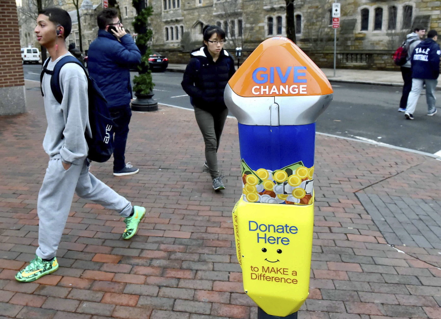Pedestrians pass one of four parking-style meters in New Haven, Conn., located in areas where panhandling has been prevalent.