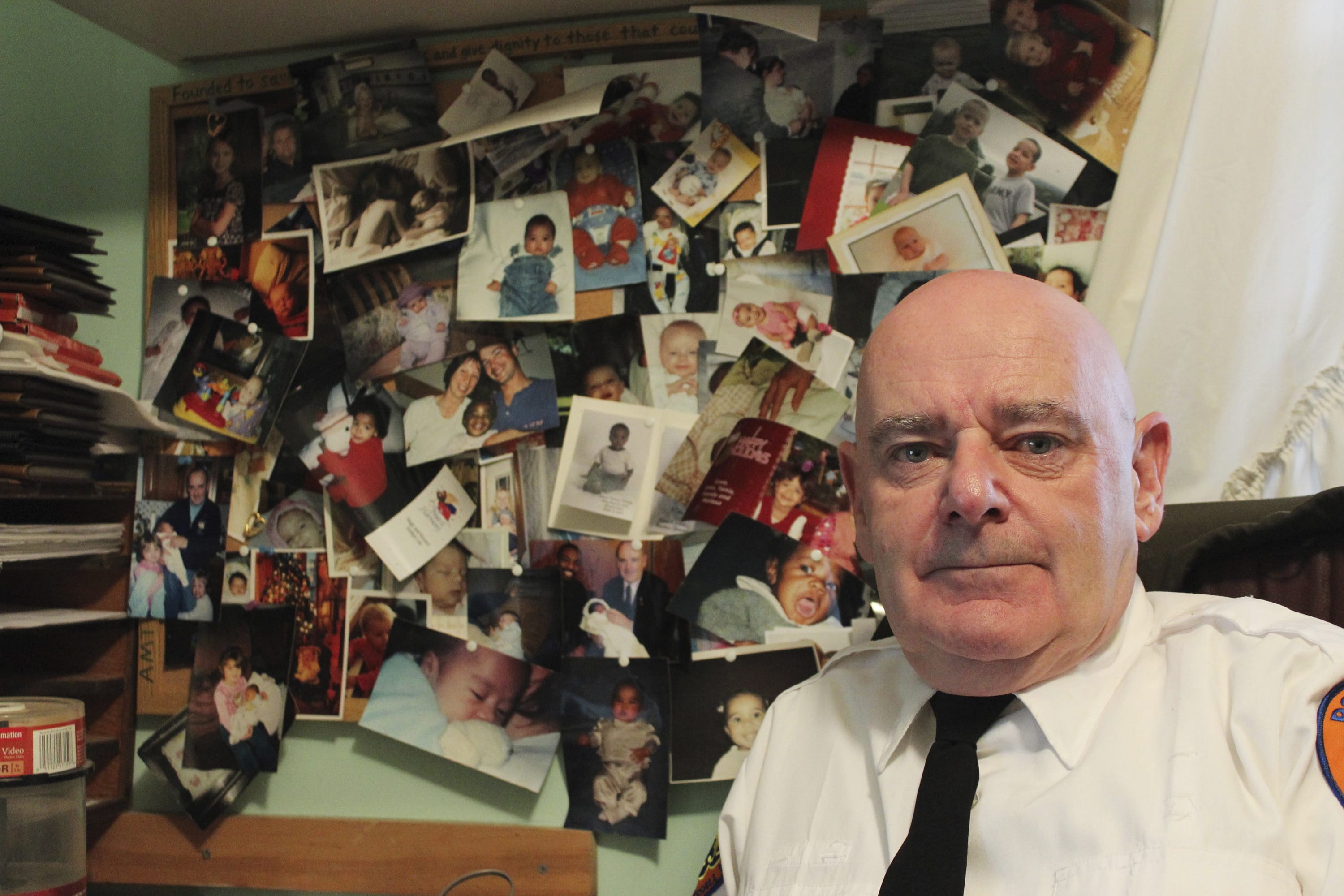 In this Dec. 12, 2016 photo, Tim Jaccard sits in front of snapshots of some of the children who were safely relinquished under a "Safe Haven" program he started 17 years ago, in Wantagh, N.Y. The retired ambulance medic lobbied legislatures across the country to pass so-called "Safe Haven" laws in all 50 states.