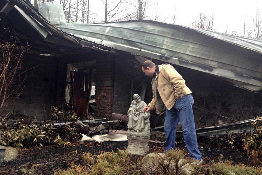 In this Monday, Dec. 6, 2016 photo, Senior Pastor Kim McCroskey inspects a statue outside the remains of the family life center at Roaring Fork Baptist Church in Gatlinburg, Tenn. The church and the center burned down in wildfires a week earlier.