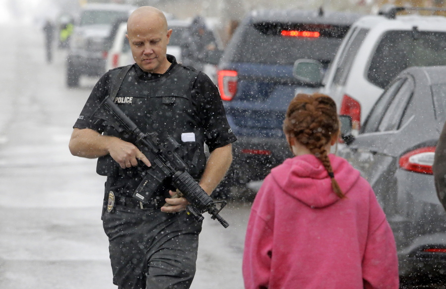 A police officer carries his weapon as he walks along the street in front of Mueller Park Junior High after a student fired a gun into the ceiling Thursday, Dec. 1, 2016, in Bountiful, Utah. Police said two fast-acting Utah parents disarmed their teenage son in the hallway of the Utah junior high school Thursday after the teenager brought the family&#039;s shotgun and handgun to school, discharging at least one round without injuring anyone.