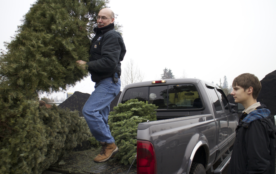 Gregg Marshall, left, unloads a tree at McFarlane&#039;s Bark in the Orchards area while Eric Knotts watches on the Boy Scouts&#039; Christmas tree recycling day in 2014.