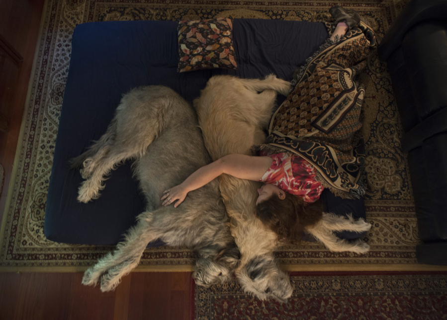Denise Harris takes an afternoon nap with her Irish Wolfhounds, Fearghus, left, and Carrik, right, in Columbia, Maryland. When Harris is feeling ill, she likes to take a nap with her canine companions on the family room floor. MUST CREDIT: Washington Post photo by Linda Davidson.