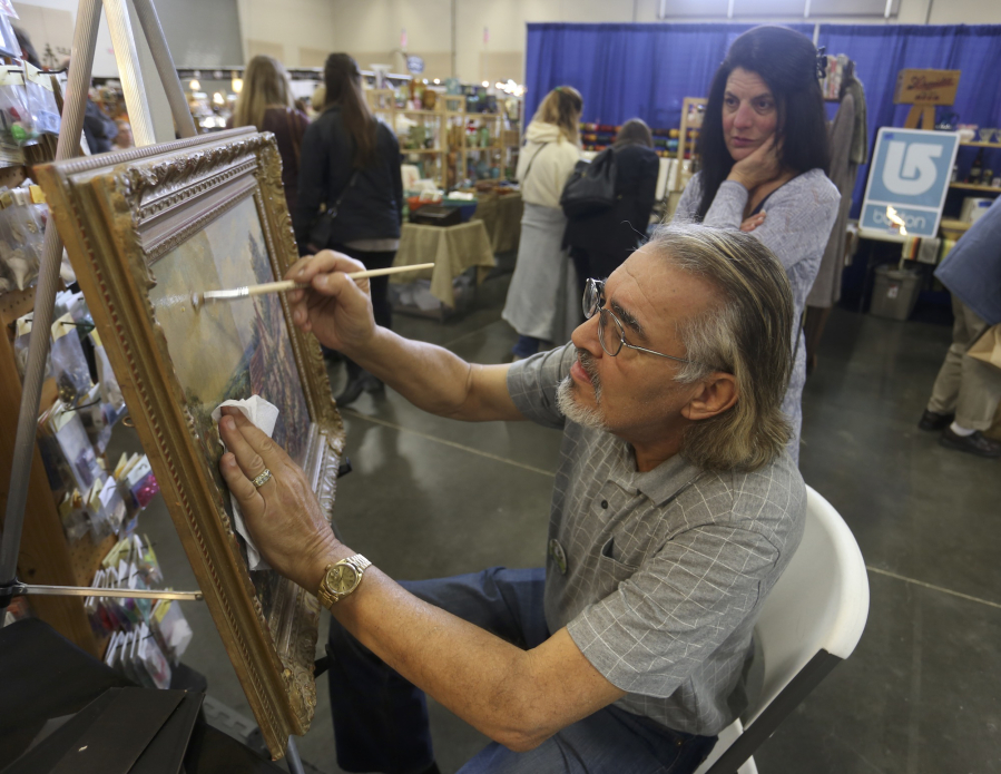 Charles Tovar of Forest Grove, Ore., restores a painting as Mary Barbaro of Portland watches Sunday at the 12th annual Clark County Antique &amp; Collectible Show.