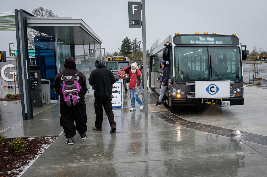Passengers cope with cold, wet weather to catch The Vine from the Vancouver Mall Transit Center on Sunday. The service operated with regular buses and on a modified route on its opening day due to adverse weather conditions.