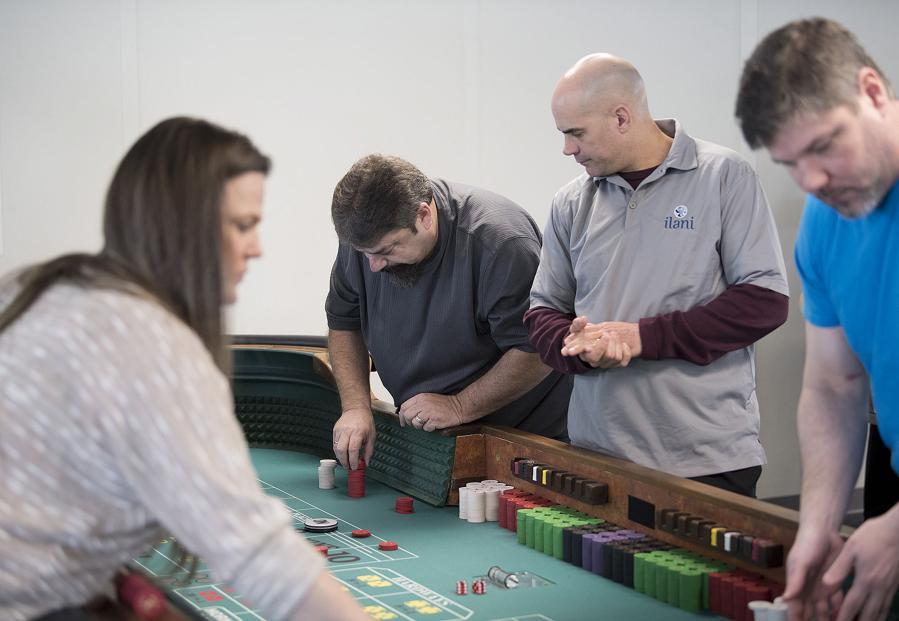 Yacolt resident Charley Cellers, second from left, learns more about the game of craps from instructor Bill Caswell, with maroon sleeves, during a class at the Ilani Casino Resort on Friday morning.