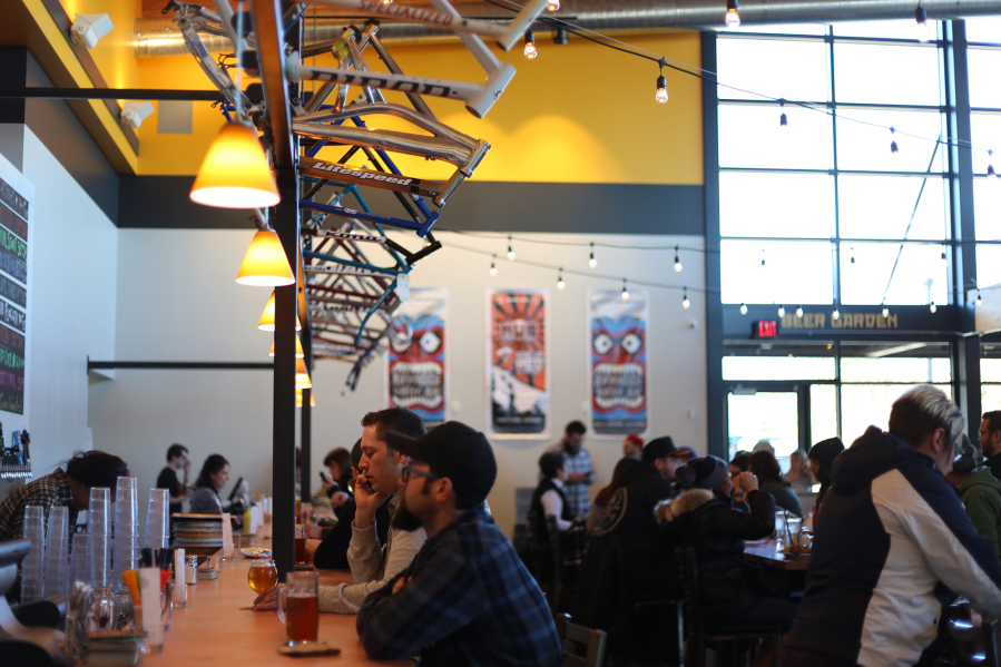 Customers eat at the bar at Hopworks Urban Brewery, under a row of bike frames. The brewery&#039;s culture of sustainability and active living has been part of its success, owner Christian Ettinger said.
