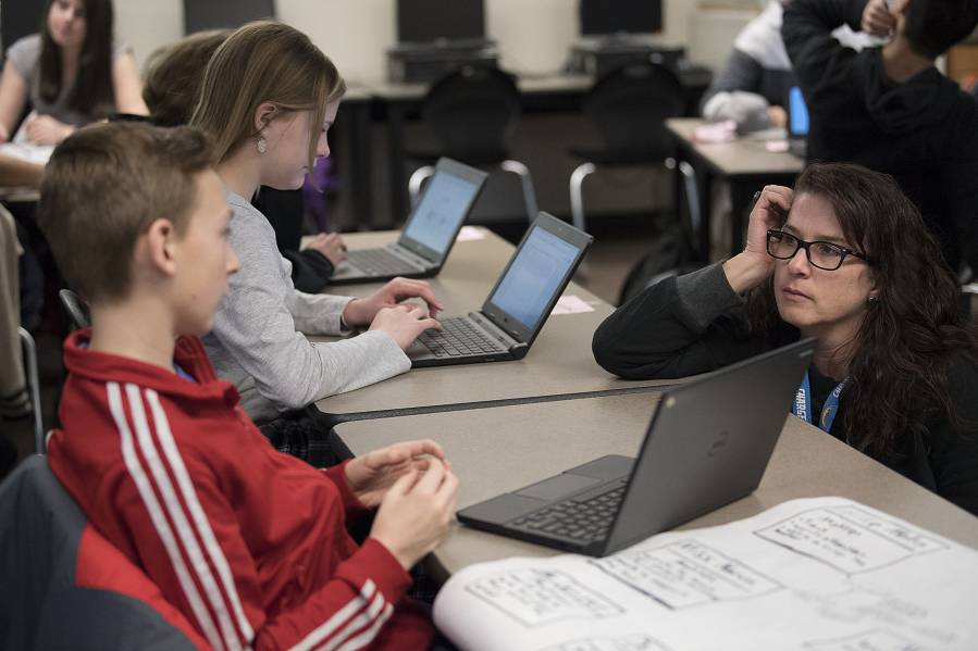 Seventh-grader Colton Sahota, 12, left, talks with teacher Beth Doughty, right, as she answers questions from students while they work on their Dell Chromebooks at Chief Umtuch Middle School in Battle Ground on Thursday morning. The district is putting a levy before voters on Feb. 14. Part of the funding supports technology in classrooms.