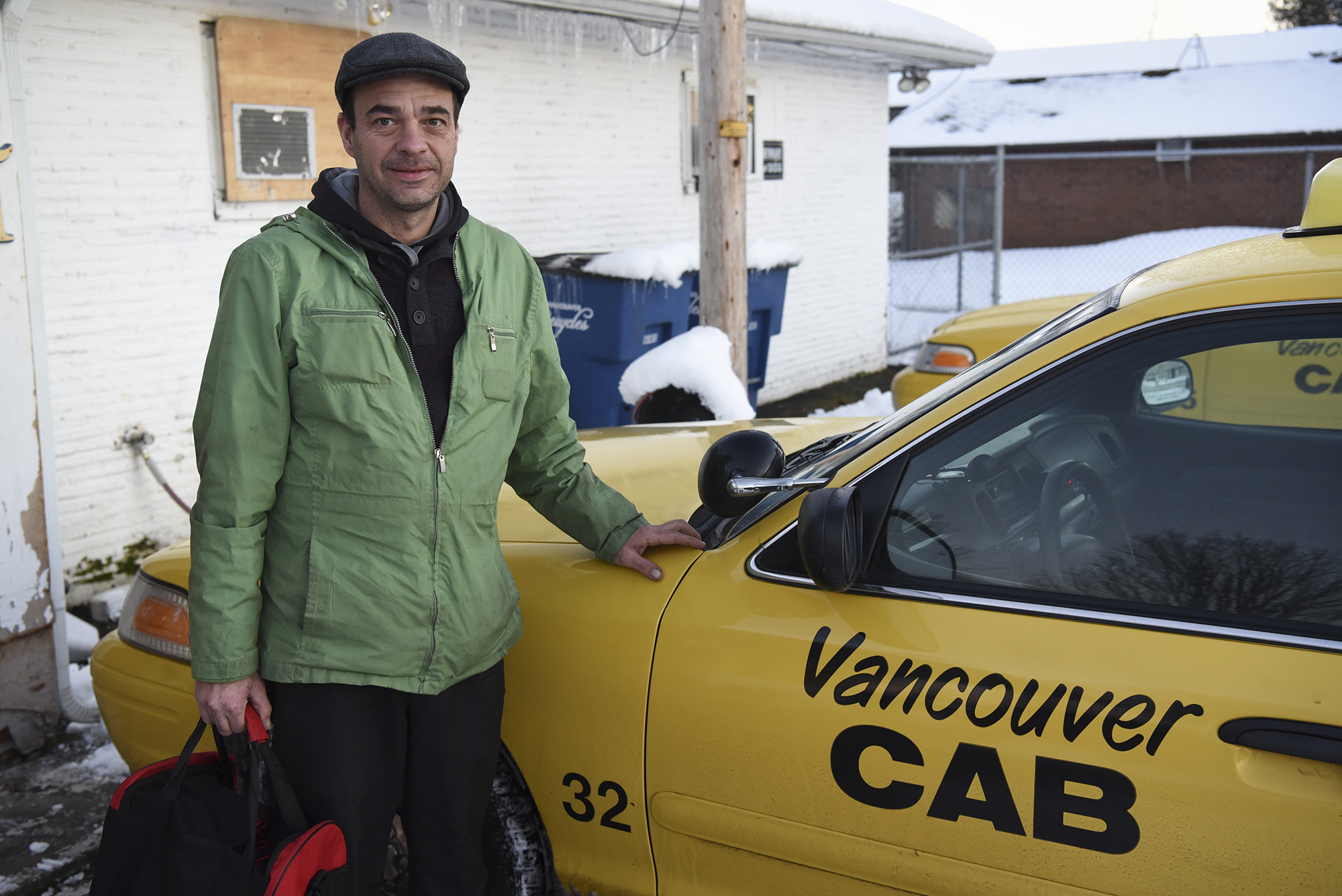 Taxi driver Jason Coffield stands outside a taxi at Vancouver Cab on Thursday evening.