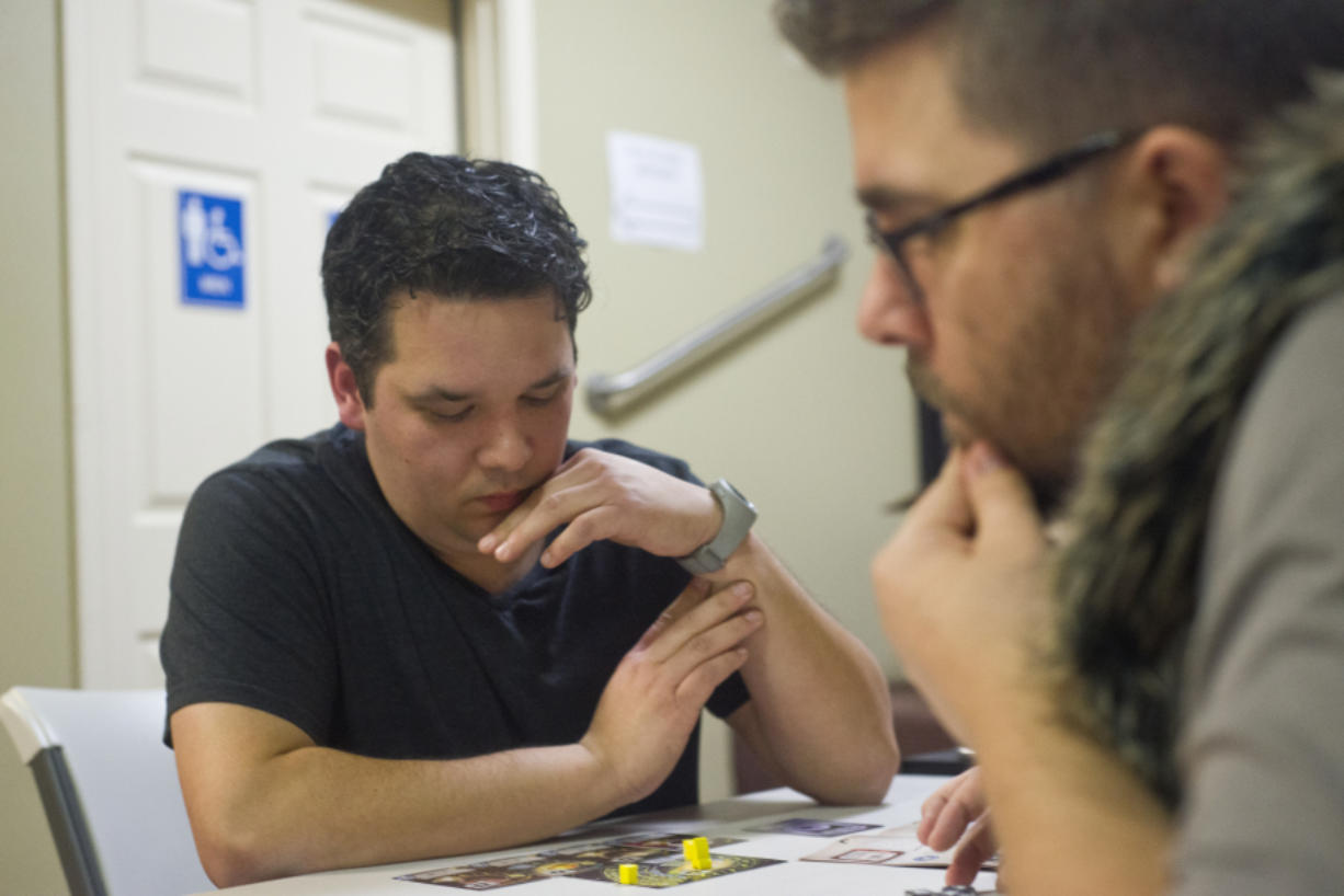 Mario Sickenberger, left, and Zak Koehler ponder their next moves during a game called Tiny Epic Galaxies at Mythic Realm Games in December. Sickenberger and Koehler are members of the Table Top and Taps group that meets for board games every Saturday in Salmon Creek.