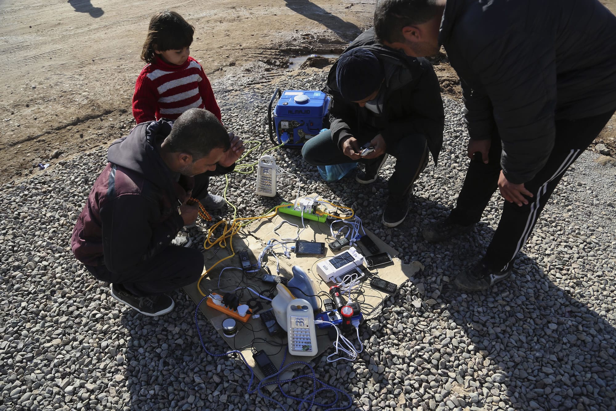 Displaced Iraqis, who fled fighting between Iraqi security forces and Islamic State militants, wait to charge their mobile phones and electrical lanterns, the generator owner charging 500 Iraqi dinars (about 45 U.S. cents) to charge each mobile phone, at Sewdinan Camp for the displaced near Khazer, Iraq on Tuesday, Jan. 3, 2017.