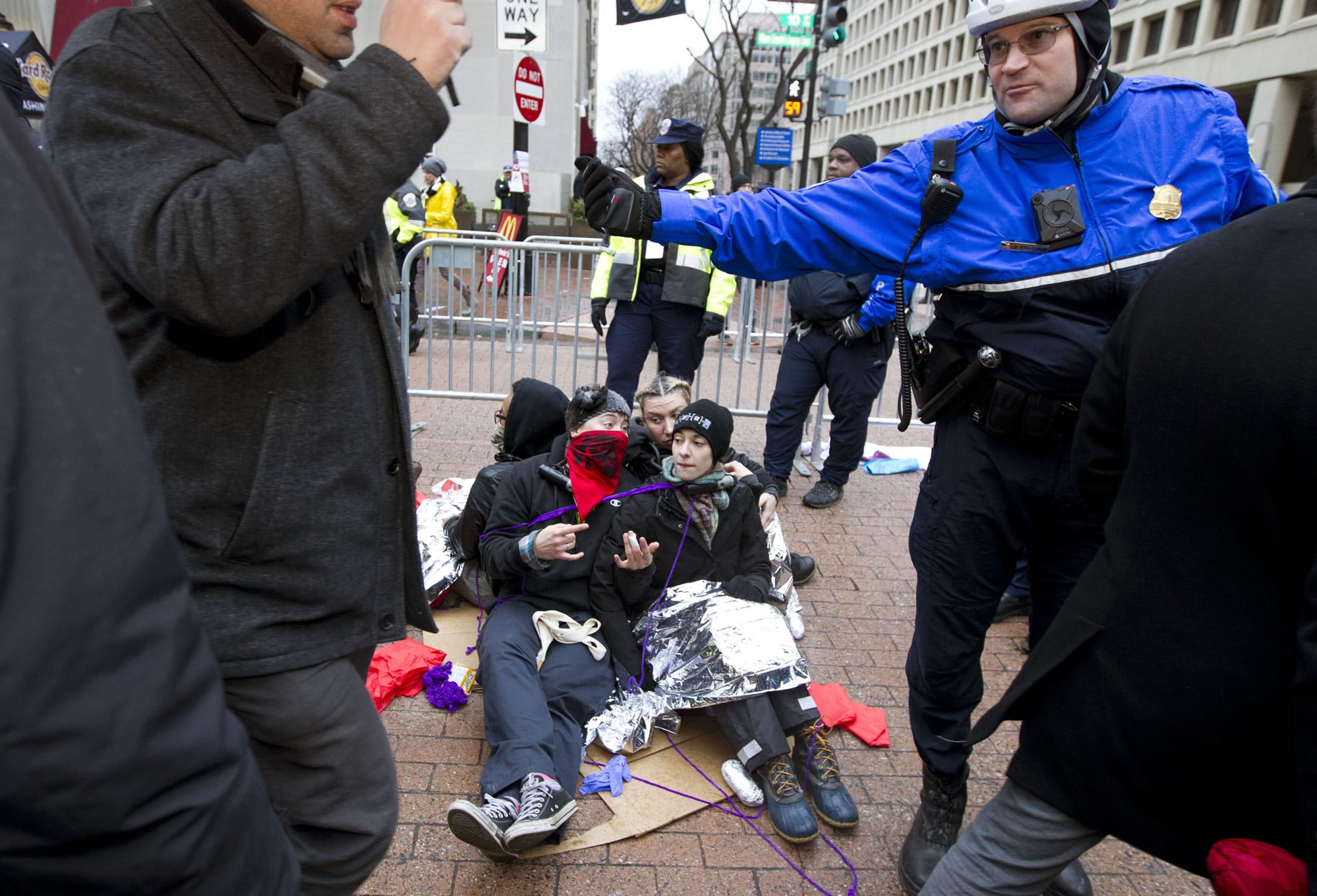 Demonstrators sit at one of the entrance as police officer let people pass let to the inauguration in Washington, Friday, Jan. 20, 2017, ahead of the President-elect Donald Trump inauguration.