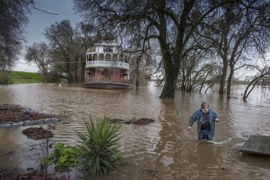 Rick Sorenson, owner of the Rio Ramaza Marina, wades in the Sacramento River on Monday after securing an old paddlewheel boat on his property as the river makes its way up the levee on Garden Highway in Sacramento, Calif.