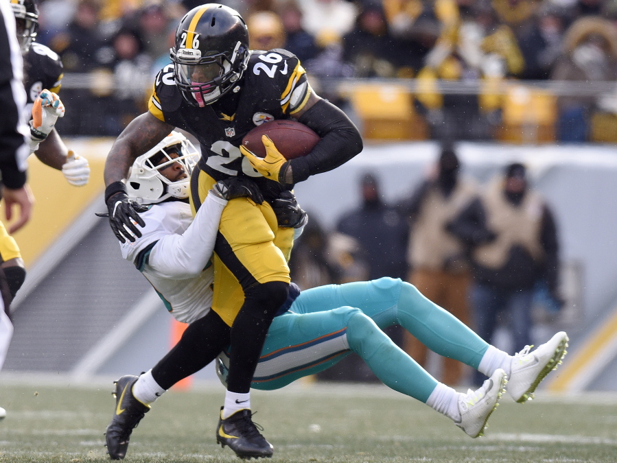 Pittsburgh Steelers running back Le&#039;Veon Bell (26) runs through a tackle by Miami Dolphins free safety Bacarri Rambo during the first half of an AFC wild-card NFL football game in Pittsburgh, Sunday, Jan. 8, 2017.