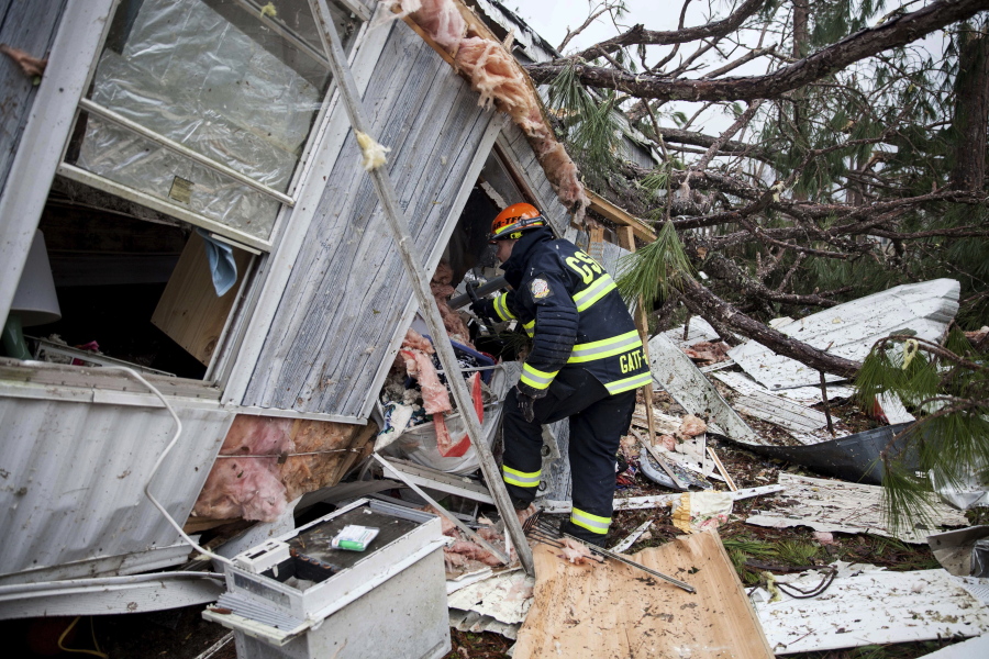 A rescue worker enters a hole in the back of a mobile home Monday in Big Pine Estates that was damaged by a tornado, in Albany, Ga. Fire and rescue crews were searching through the debris, looking for people who might have become trapped.