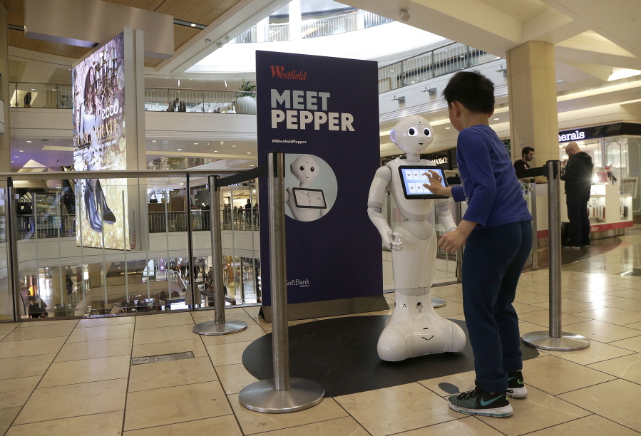 In this Thursday, Dec. 22, 2016, photo, a boy plays with Pepper the robot at Westfield Mall in San Francisco. While merrily chirping, dancing and posing for selfies, Pepper looks like another expensive toy in the San Francisco mall where it will be entertaining shoppers through mid-February. But it would be a mistake to dismiss Pepper as mere child&#039;s play, even though kids flock around the 4-foot-tall humanoid as it speaks in a cherubic voice that could belong to either a boy or girl.