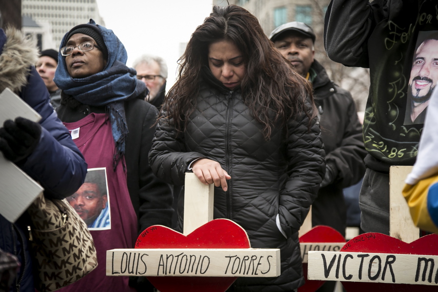 Veronica Aguilera, 31, carries the cross for her husband, Louis Antonio Torres, who was shot to death in November, during a quiet march along Michigan Avenue, Saturday, Dec. 31, 2016, in Chicago. Hundreds of people carried crosses for each person slain in Chicago in 2016 during the march.