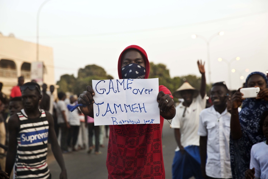 A man holds a banner Thursday as Gambians cheers in Serrekunda, Gambia, after watching Adama Barrow be sworn in as Gambian president on a television broadcast from the Gambian Embassy in Dakar, Senegal.