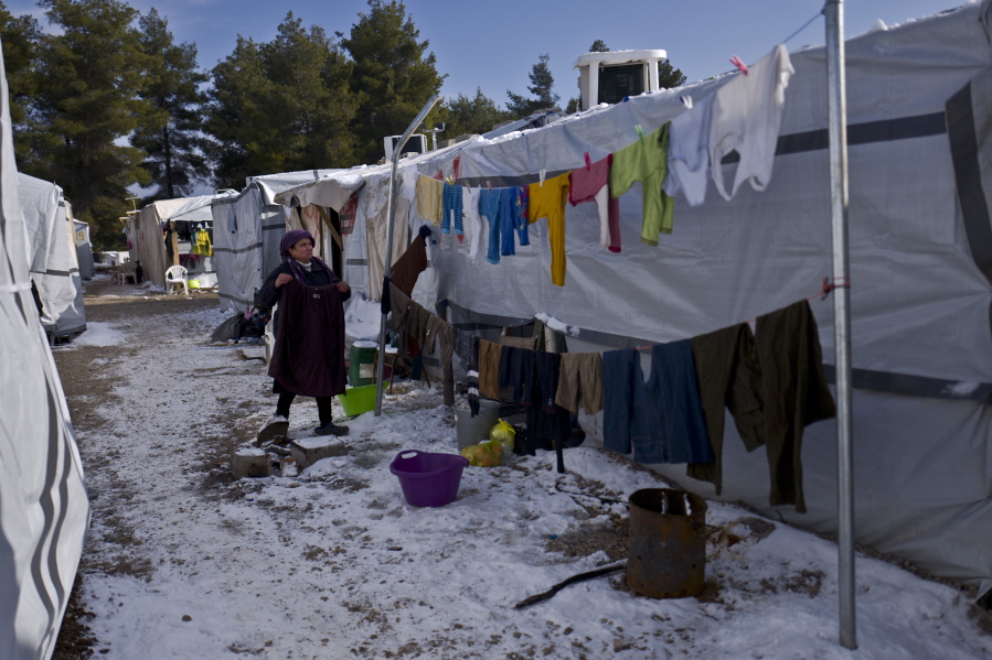 A Syrian refugee woman hangs her laundry in front of her shelter at the refugee camp of Ritsona about 86 kilometers north of Athens on Monday. More than 62,000 refugees and migrants are stranded in Greece after a series of Balkan border closures and an European Union deal with Turkey to stop migrant flows.