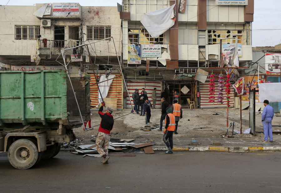 Municipality workers clean up debris a day after a car bomb explosion in Abu Dshir southern Baghdad, Iraq, Wednesday, Jan. 18, 2017.