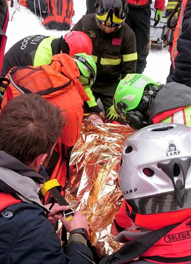 A woman gets assistance after being pulled out from the hotel that was hit by an avalanche on Wednesday, in Rigopiano, central Italy, Friday, Jan. 20, 2017. Rescue crews located more than eight people alive in the rubble of an avalanche-crushed hotel on Friday, an incredible discovery that boosted spirits two days after the massive snow slide buried around 30 people in the resort.