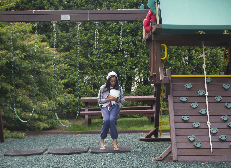 Malia Obama uses her phone at the swing and play set on the south grounds of the White House outside of the Oval Office in Washington in May. The swing set that President Barack Obama installed on the South Lawn for his young daughters eight years ago has a new home. The White House says the Obamas donated the set to a shelter in southeast Washington. The Obamas are planning to visit the Jobs Have Priority Naylor Road Program and join residents for a service project Monday in honor of Martin Luther King Jr. Day.