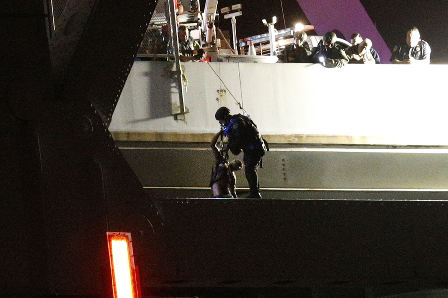 Sylvester Holt, left, is lifted of the ledge of the Crescent City Connection by an officer Friday, Jan. 20, 2017, in New Orleans. Holt was wanted in the connection with the shooting of his wife and a Westwego police officer.