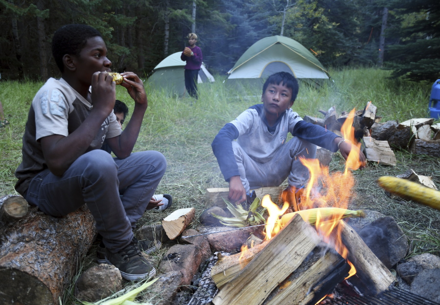 Justin Mbelechi, 13, and Bidesh Magar, 14, roast corn Sept. 10 at their campsite in Evergreen, Colo. The two belong to a Colorado Boy Scout troop that is made up almost entirely of refugees. At campouts, traditional American food like hot dogs and trail burgers is replaced by fish head stew, fire-roasted corn and Chatpate, a popular Nepalese street snack.